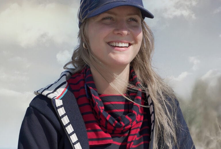 Vrouw met pet glimlacht buiten in wind